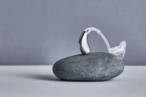 Behind-The-Ear aid rests on a smooth stone, demonstrating modern health hea.. Stock-Fotos
