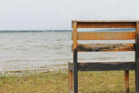 Behind the empty bench by the lake in the park. Stock Photos