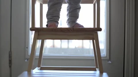 From behind, this image shows tiny bare feet of a toddler standing on a woode Stock Footage 275799668
