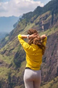 From behind of lady in yellow jacket posing at landmark nature background, Sr Foto stock