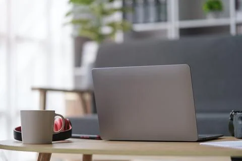 Behind of laptop computer, cup of coffee and headphone on wooden table in l.. Stock Photos