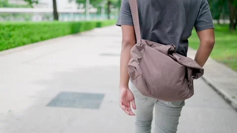 Behind, Man is walking with his hands in his pants and holding a laptop Stock Footage 283186869