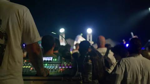 Behind-the-mixer view showing operator with crowd, stage and performing artist Stock Footage 313789222