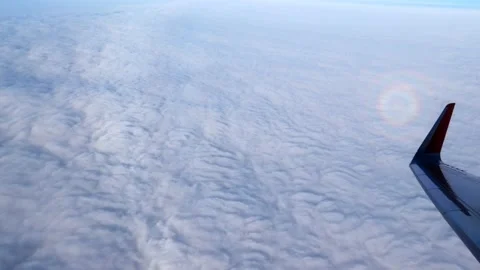 Behind the plane, multicolored sun glare on the clouds moves. An airplane wing Stock Footage 166028571
