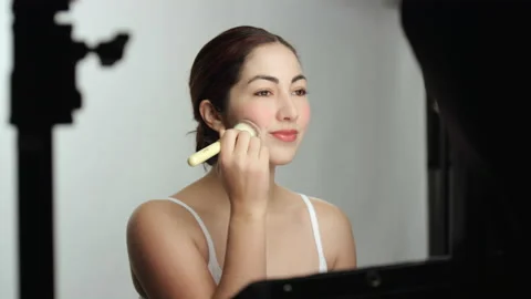 Behind the scenes dolly shot of model applying blush makeup with brush 스톡 동영상 193899091