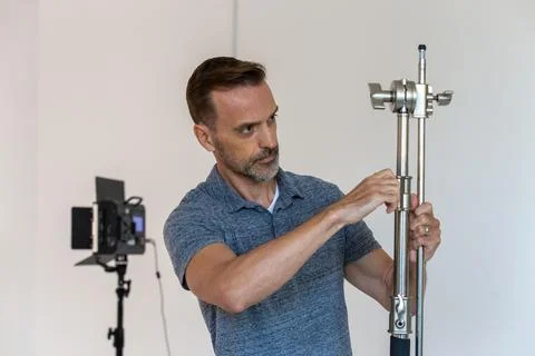 Behind the Scenes of Man Setting Up C-stand on a Video Production Set Foto stock