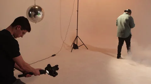 Behind the scenes of a videographer filming a man walking through smoke in a Stock Footage 344166393