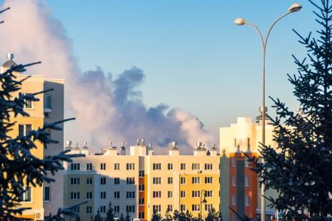 Behind the trees a large cloud of smoke above the roofs of multi-storey build Stock Photos