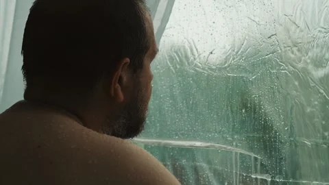 Behind the window, a man contemplates the rain with a heavy heart Stock Footage 308019157