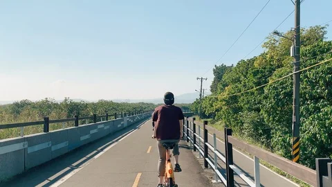 Behind young man swerving with his bicycle in the middle of the beautiful road Video stock 103402681