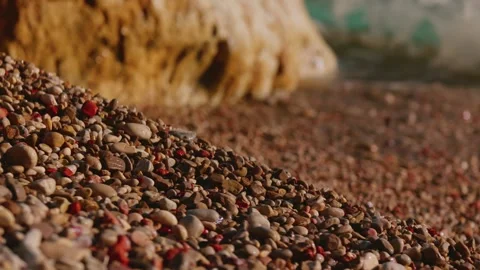 Beige and brown pebbles with red fragments lead to a golden rocky outcrop as Stock Footage 329411966