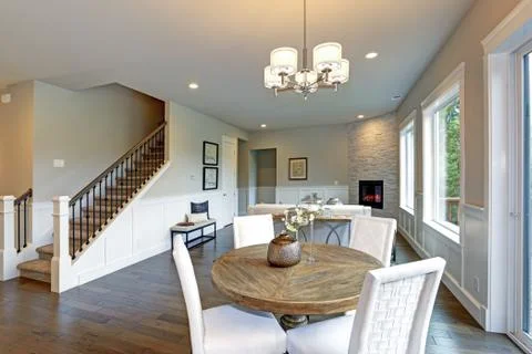 Beige and white dining space boasts a rustic round wood Table surrounded by w Stock Photos