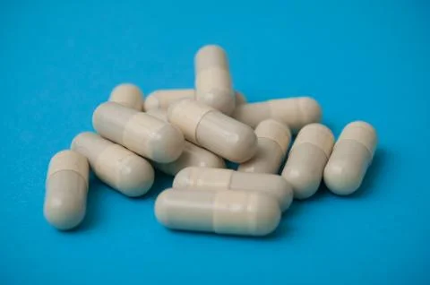 Beige capsules on blue background Stock Photos