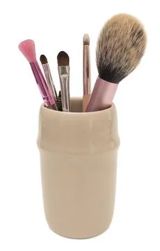 Beige ceramic holder filled with various makeup brushes, including powder, .. Stock Photos