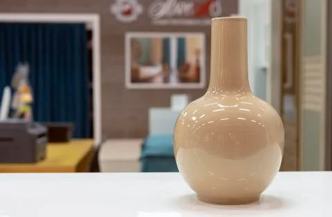 Beige ceramic vase of simple form on a white table. Foto stock