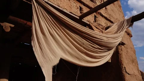 Beige cloth draped over mud brick wall in desert village Vídeo Stock 347972713