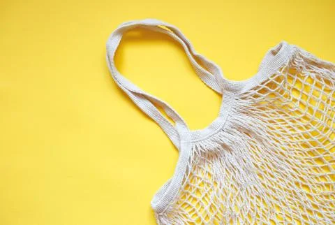 Beige cotton string knitted bag on yellow background. Stock Photos