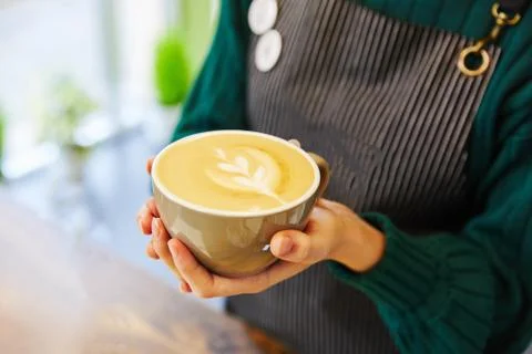 Beige cup of coffee with a pattern in the hands of a man Stock Photos