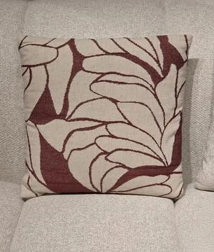 Beige decorative pillow with red pattern on sofa Stock Photos