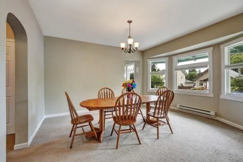 Beige dining room interior with round wall, carpet floor, wooden table with c Stock Photos