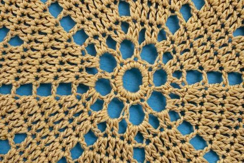Beige doily crochet pattern on blue background, abstract close up texture Stock Photos
