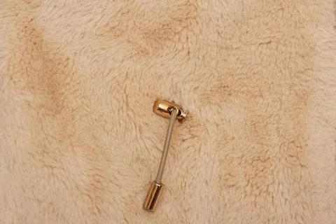 Beige drawstring with metal gold jacket fastener, on fur background. Stock Photos