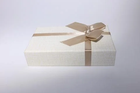Beige gift box, with a brown bow, isolated on a white background. Stock Photos