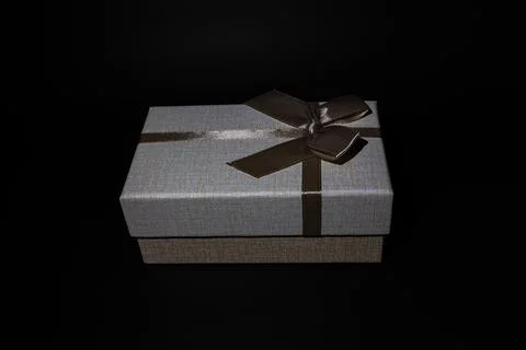 Beige gift box, with a brown bow, isolated on a black background Stock Photos