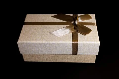 Beige gift box, with a brown bow, isolated on a black background Foto stock