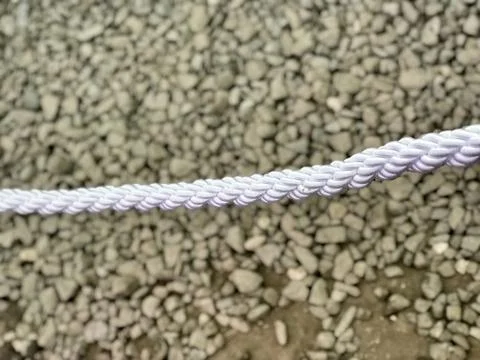 Beige ground surface with small stones and white rope above it Stock Photos