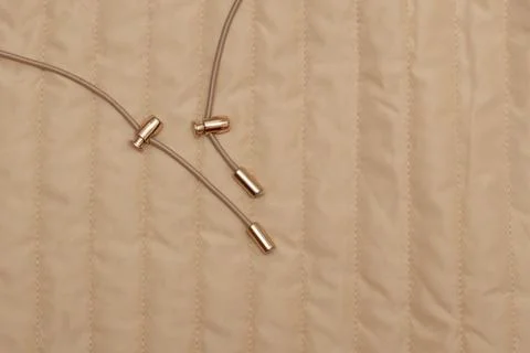 Beige jacket drawstring with metal lock. Stock Photos