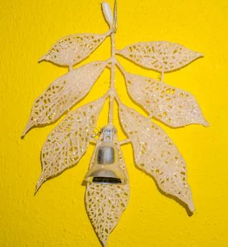 Beige leaf with beads and bell on yellow background close up indoor Stock Photos