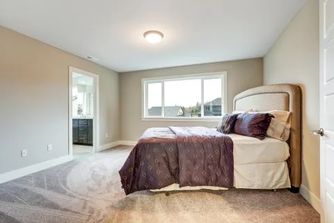 Beige master bedroom with king size bed accented with upholstered headboard a Stock Photos