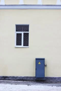 Beige outer wall of the house, window and transformer cabinet. Stock Photos