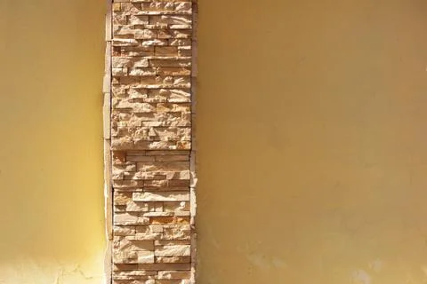 Beige plastered wall with an insert of natural limestone of the same color Stock Photos