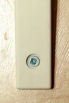 A beige plastic electrical wall switch with silver screw on wood surface Stockfoto's