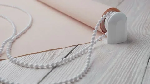 Beige roller blind and spare parts on a white wooden table. Stock-Footage 147961871