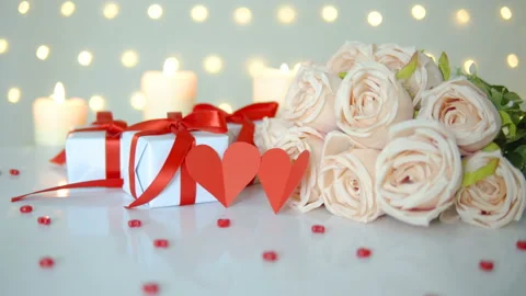 Beige rose bouquet, gift boxes and candles on bokeh lights background for v.. Stock Footage 236740939