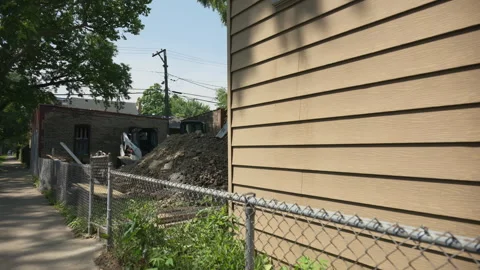 Beige siding and chain-link fence. In the background, construction work is Stock Footage 317734320