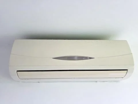 Beige split air conditioner unit installed indoors on a plain white wall Photos