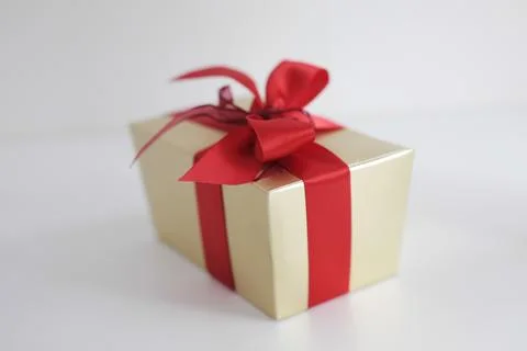 Beige square gift box with red bow on white background Фото