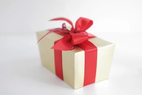 Beige square gift box with red bow on white background Стоковые фото