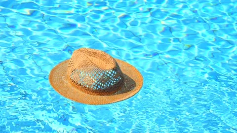 A beige straw summer hat swims in an empty blue water pool. The concept Video stock 147947105