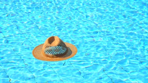 A beige straw summer hat swims in an empty blue water pool. concept of summer Stock Footage 147947207