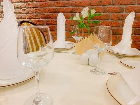 On a beige tablecloth there is a table service, plates and glasses and Stock Photos