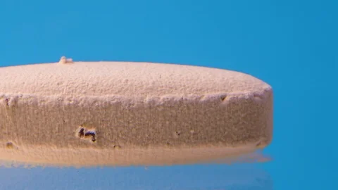 Beige Tablet dissolves in water on blue background. Stock Footage 119062750