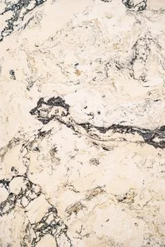 Beige texture of a marble surface with black streaks close-up. Stock Photos