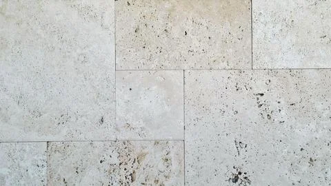 Beige travertine stone wall with rectangular blocks and porous texture Stock Photos