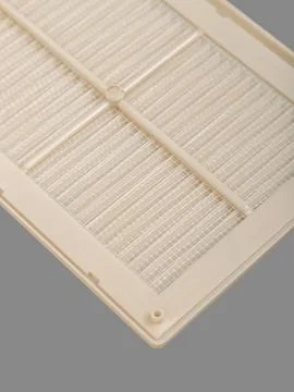 Beige ventilation grate on a gray background. Close-up. Material is plastic.  Stock Photos