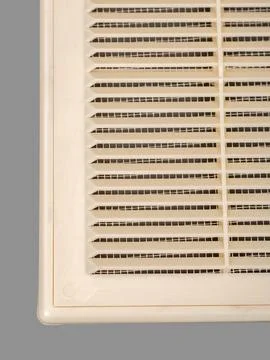 Beige ventilation grate on a gray background. Close-up. Material is plastic. Stock Photos